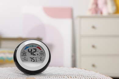 Photo of Digital hygrometer with thermometer on mat in room. Space for text