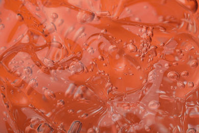 Pure transparent cosmetic gel on orange background, closeup