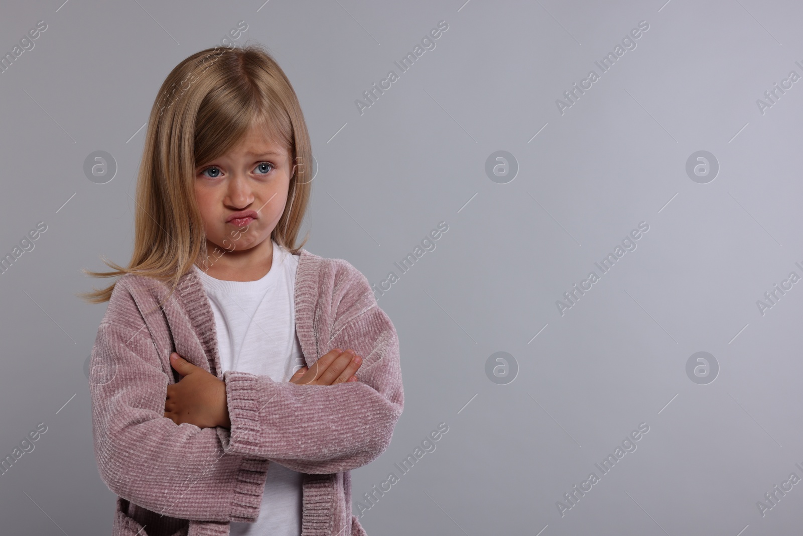 Photo of Resentful girl with crossed arms on grey background. Space for text