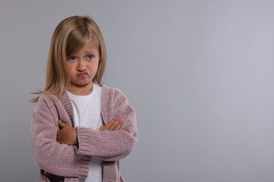 Photo of Resentful girl with crossed arms on grey background. Space for text