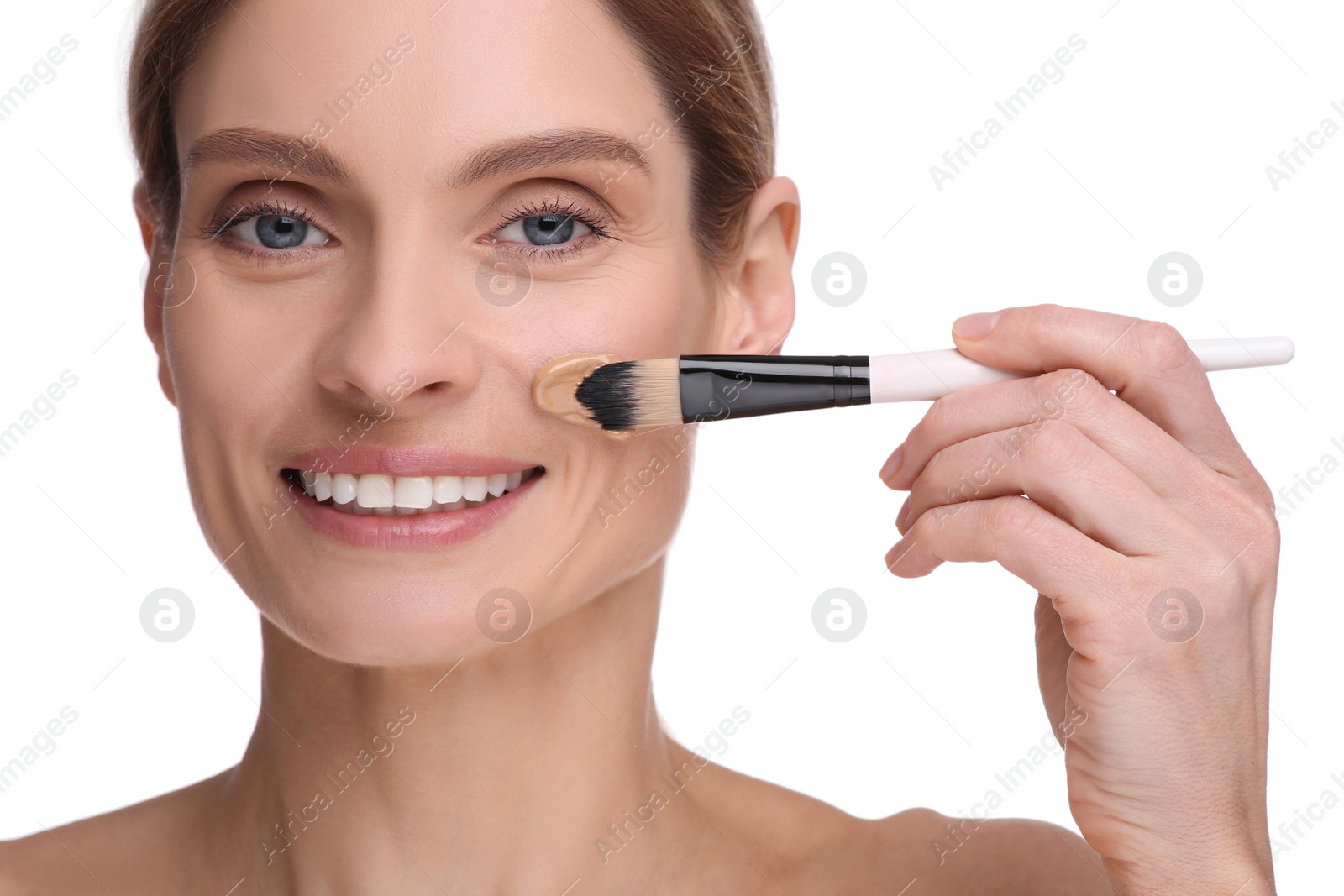 Photo of Woman applying foundation on face with brush against white background