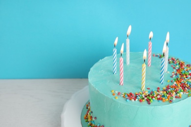 Fresh delicious birthday cake with candles on table against color background. Space for text