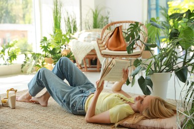 Happy young woman reading book on floor at indoor terrace