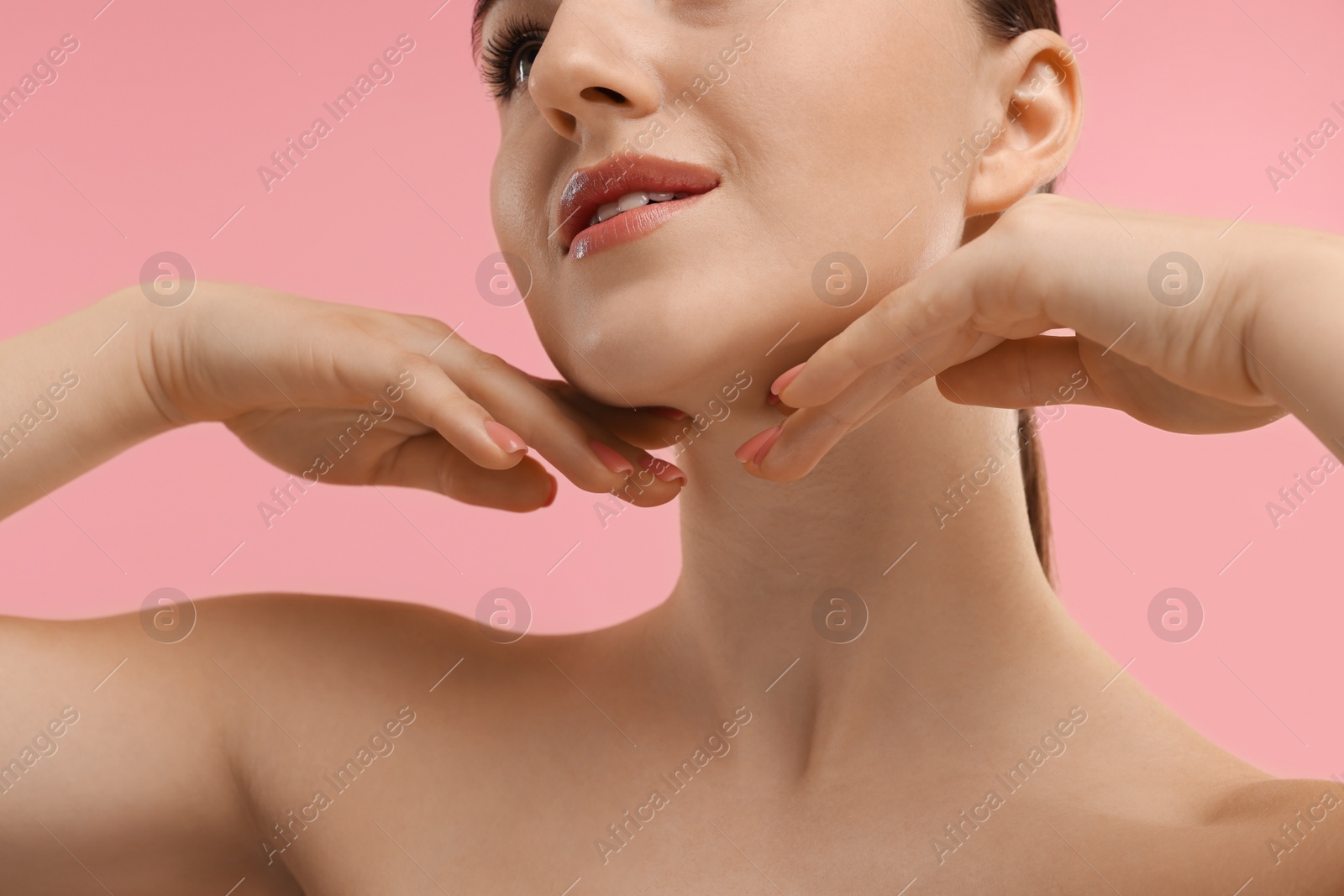 Photo of Woman touching her chin on pink background, closeup