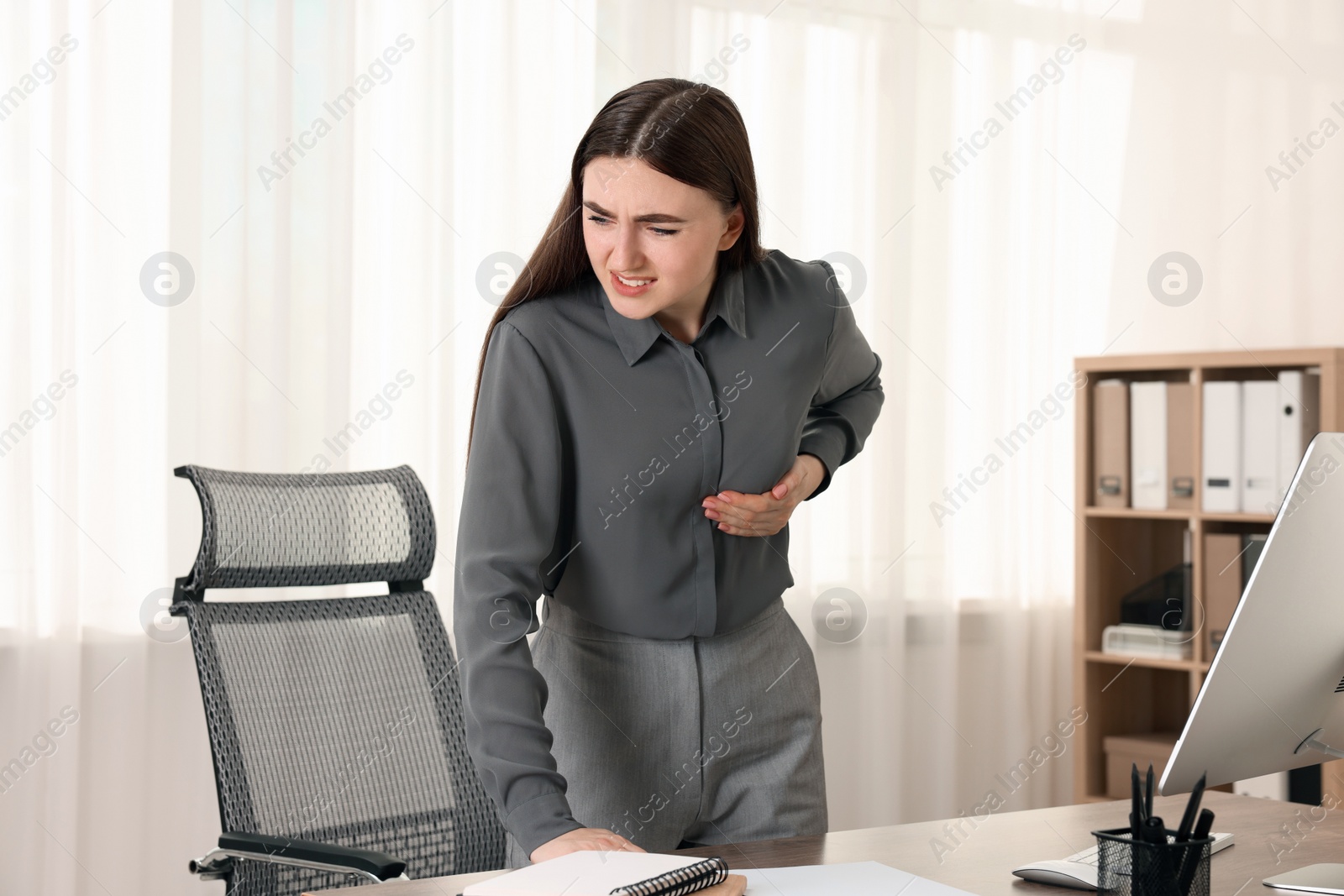 Photo of Woman having heart attack near table in office
