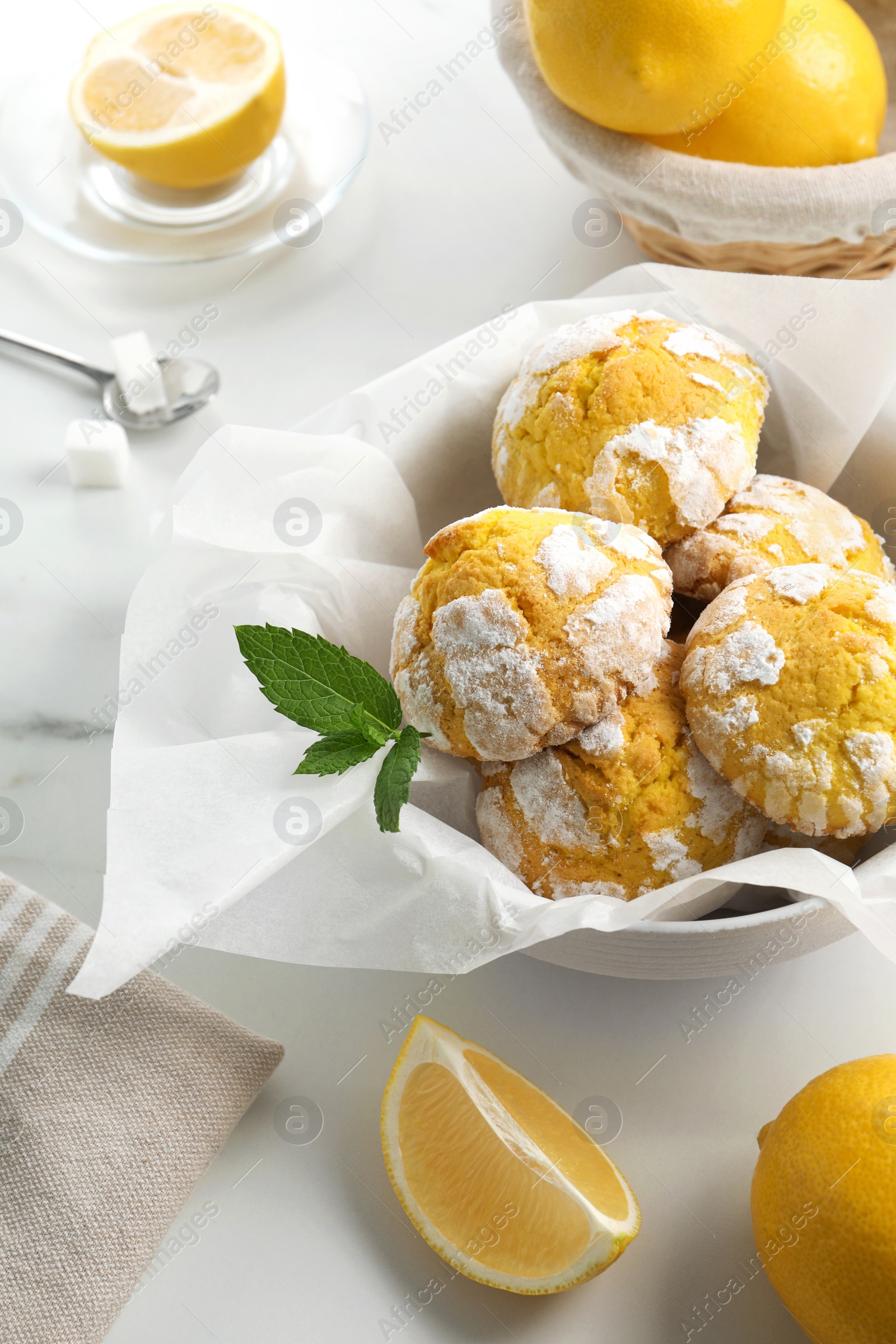 Photo of Tasty homemade lemon cookies with fresh fruit and mint on white marble table