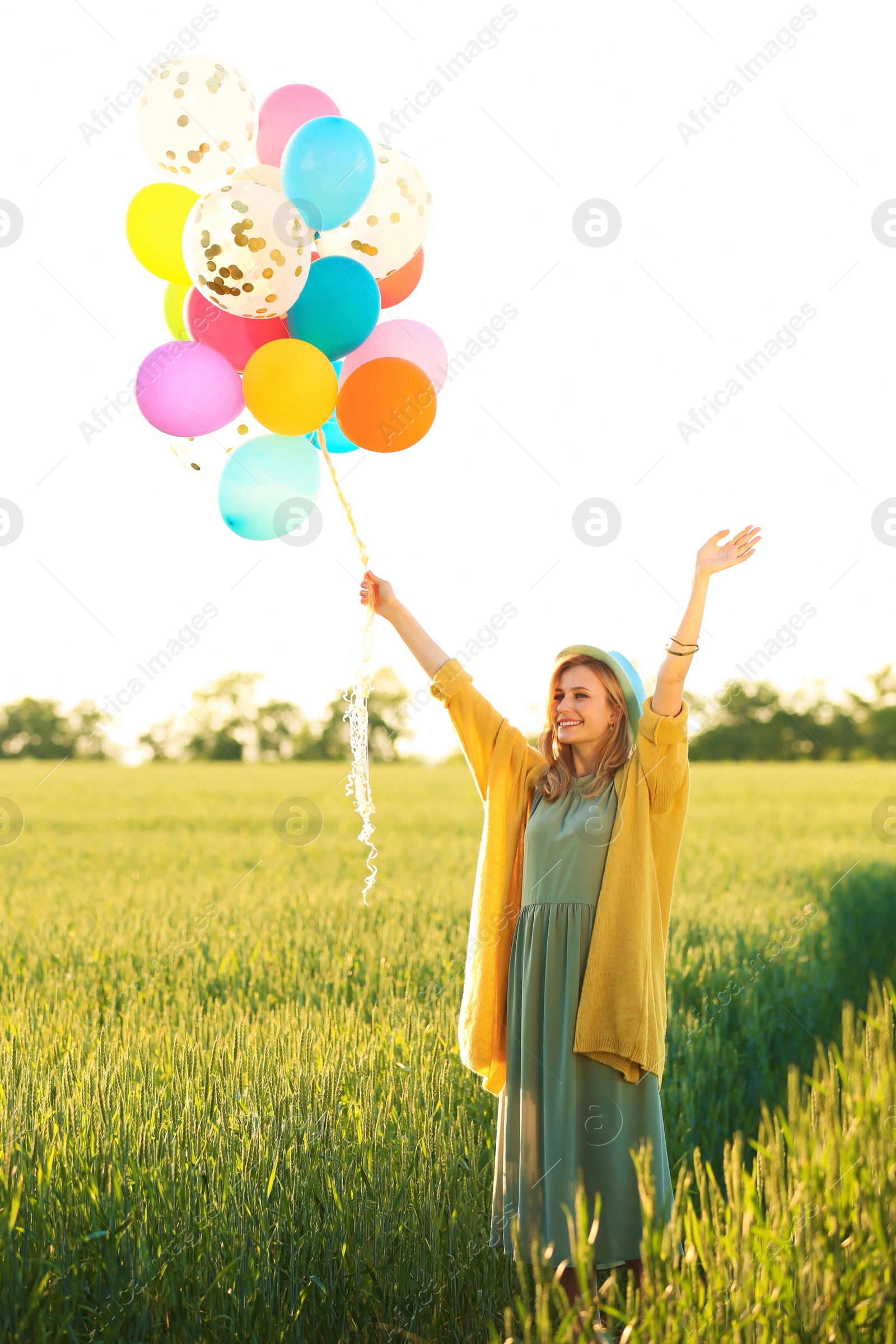 Photo of Young woman with colorful balloons in field on sunny day