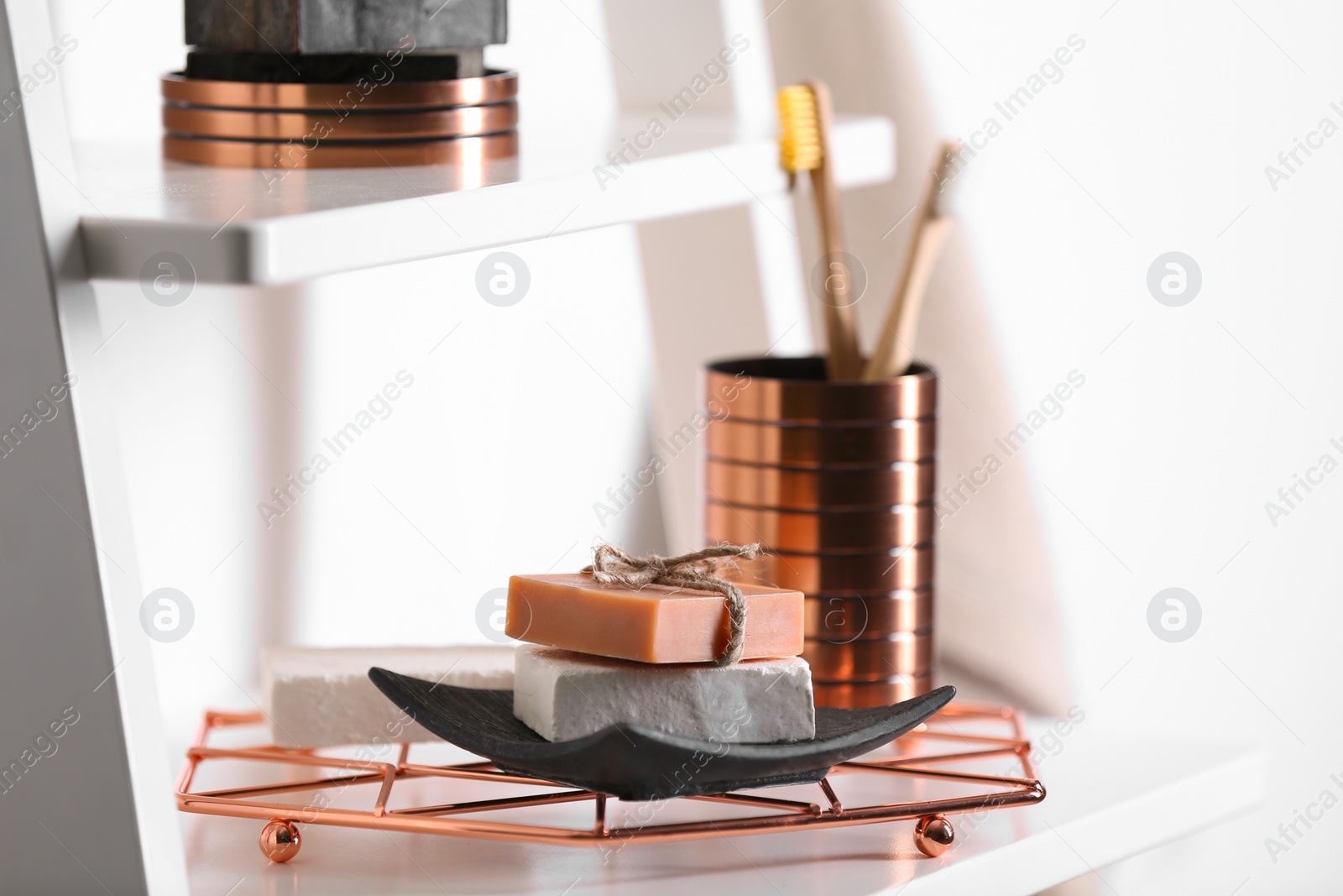 Photo of Soap bars and toiletries on shelf against light background