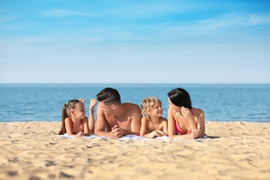 Photo of Happy family on sandy beach near sea. Summer holidays