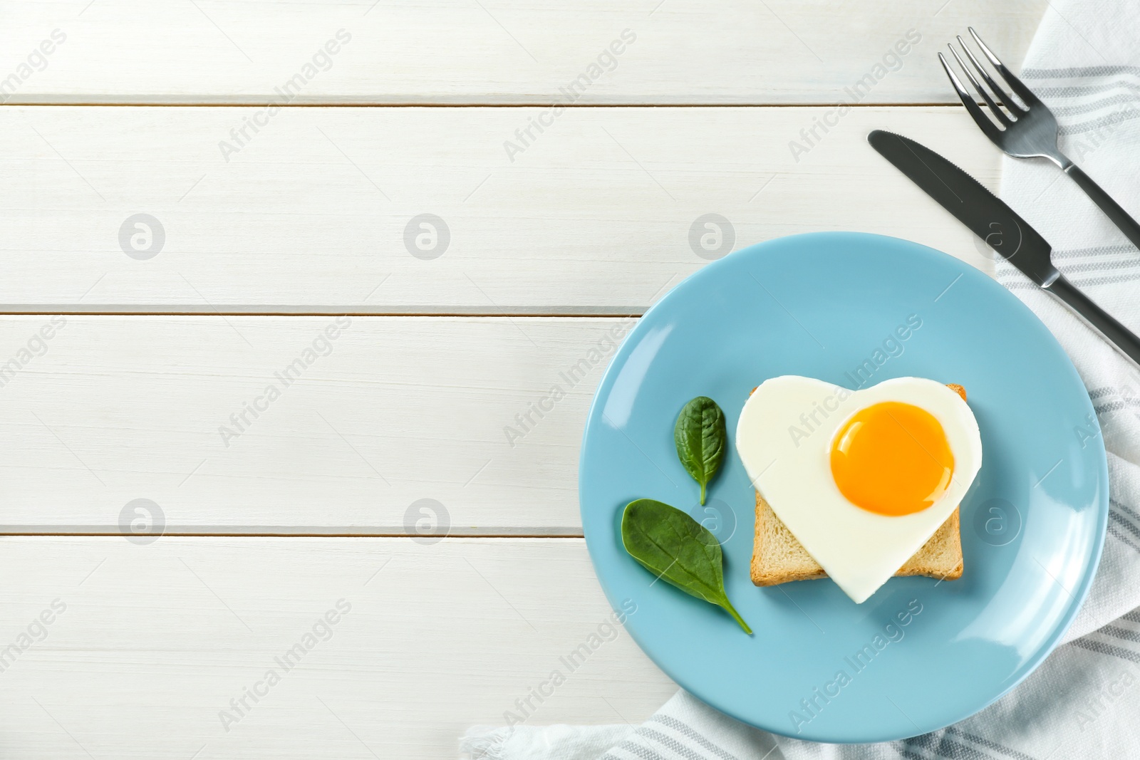 Photo of Romantic breakfast with heart shaped fried egg served on white wooden table, flat lay. Space for text