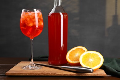 Photo of Aperol spritz cocktail and ice cubes in glass and bottle on wooden table