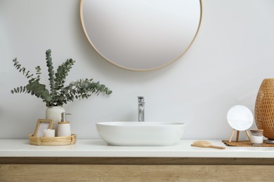 Photo of Stylish mirror, eucalyptus branches and vessel sink in modern bathroom. Interior design