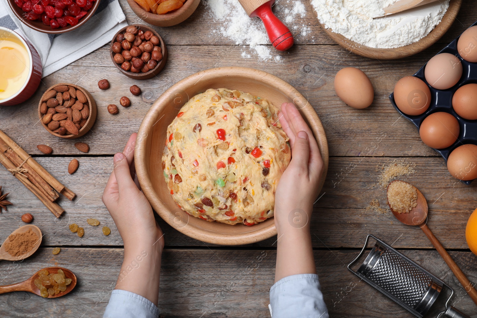 Photo of Woman kneading dough for Stollen at wooden table, top view. Baking traditional German Christmas bread