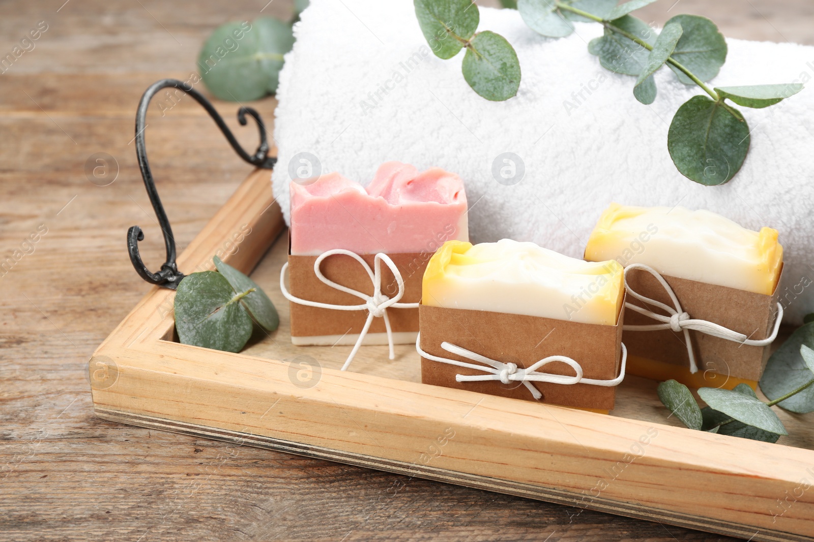 Photo of Natural handmade soap bars in tray on wooden table, closeup