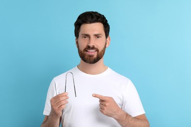 Smiling man showing tongue cleaner on light blue background