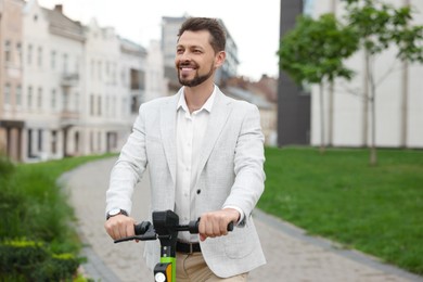 Businessman with modern kick scooter on city street