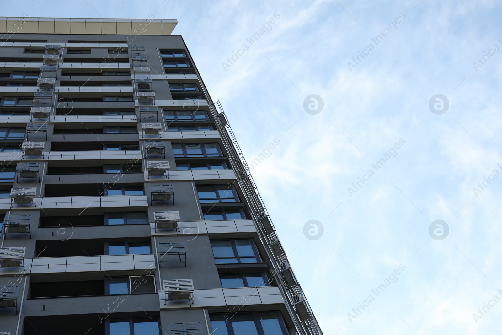 Photo of Modern building with big windows against blue sky outdoors, low angle view. Space for text