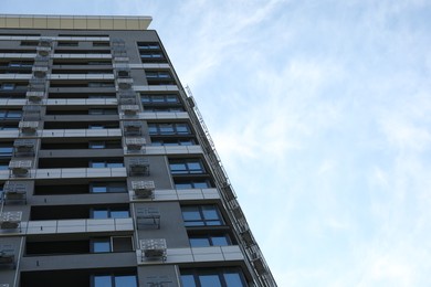 Modern building with big windows against blue sky outdoors, low angle view. Space for text