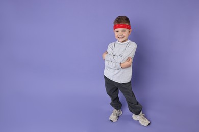 Photo of Happy little boy dancing on violet background. Space for text