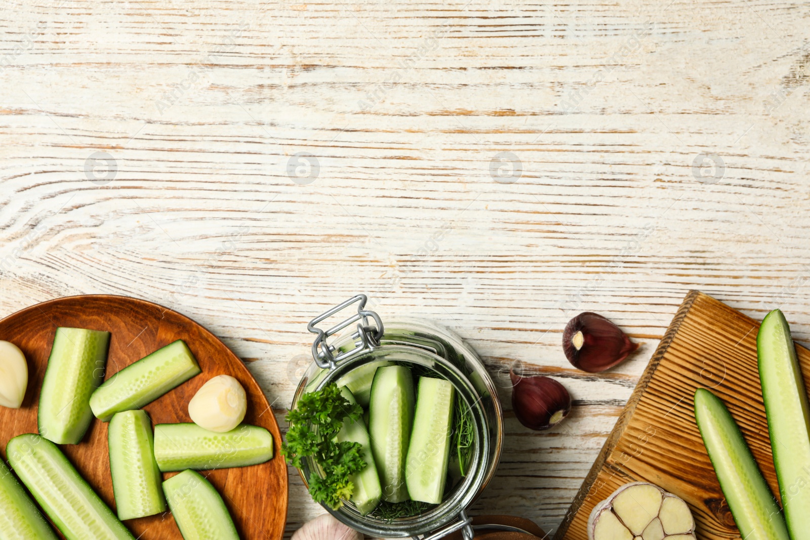 Photo of Pickling jar with fresh ripe cucumbers and spices on white wooden table, flat lay. Space for text