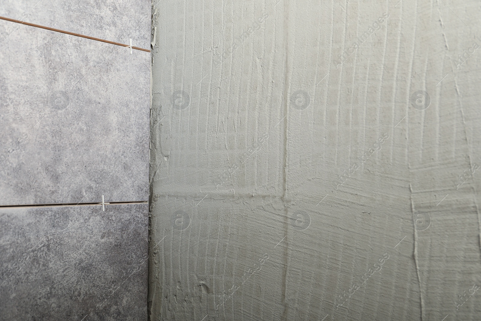 Photo of Adhesive mix and ceramic tiles on wall, closeup