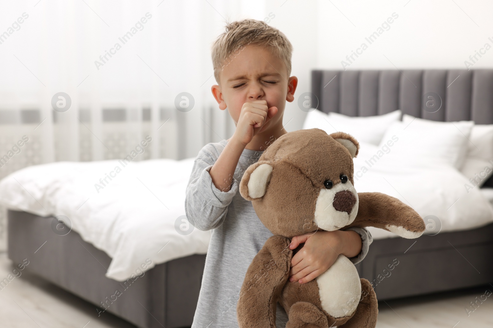 Photo of Sick boy with teddy bear coughing at home