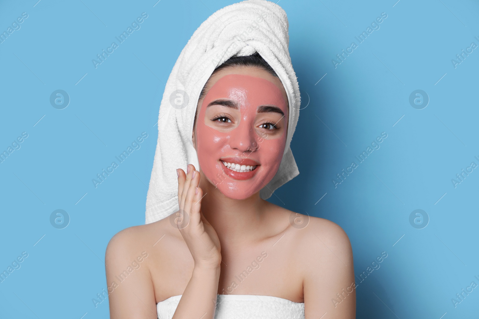 Photo of Woman with pomegranate face mask on light blue background