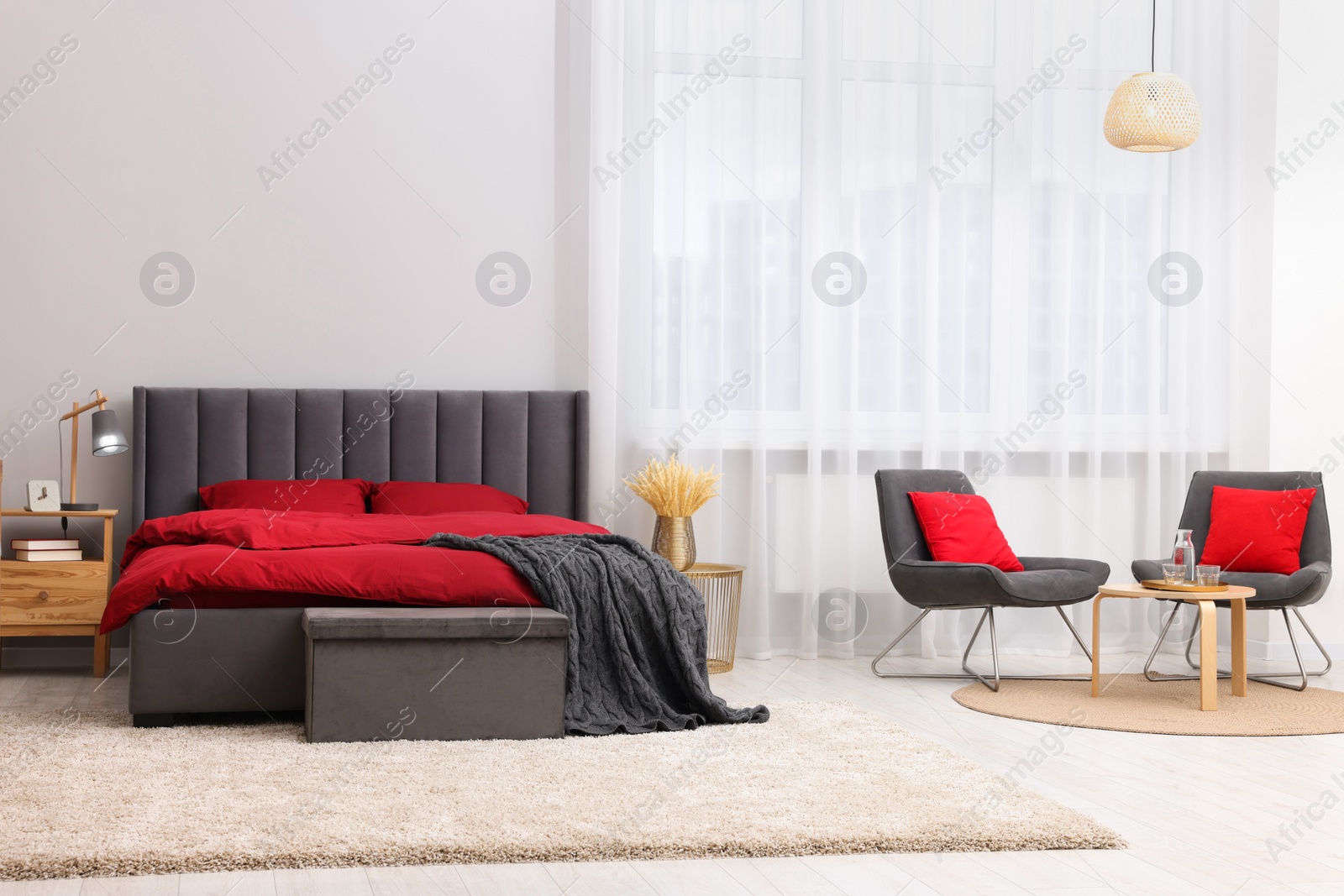 Photo of Stylish bedroom with comfortable bed, armchairs and table. Interior design