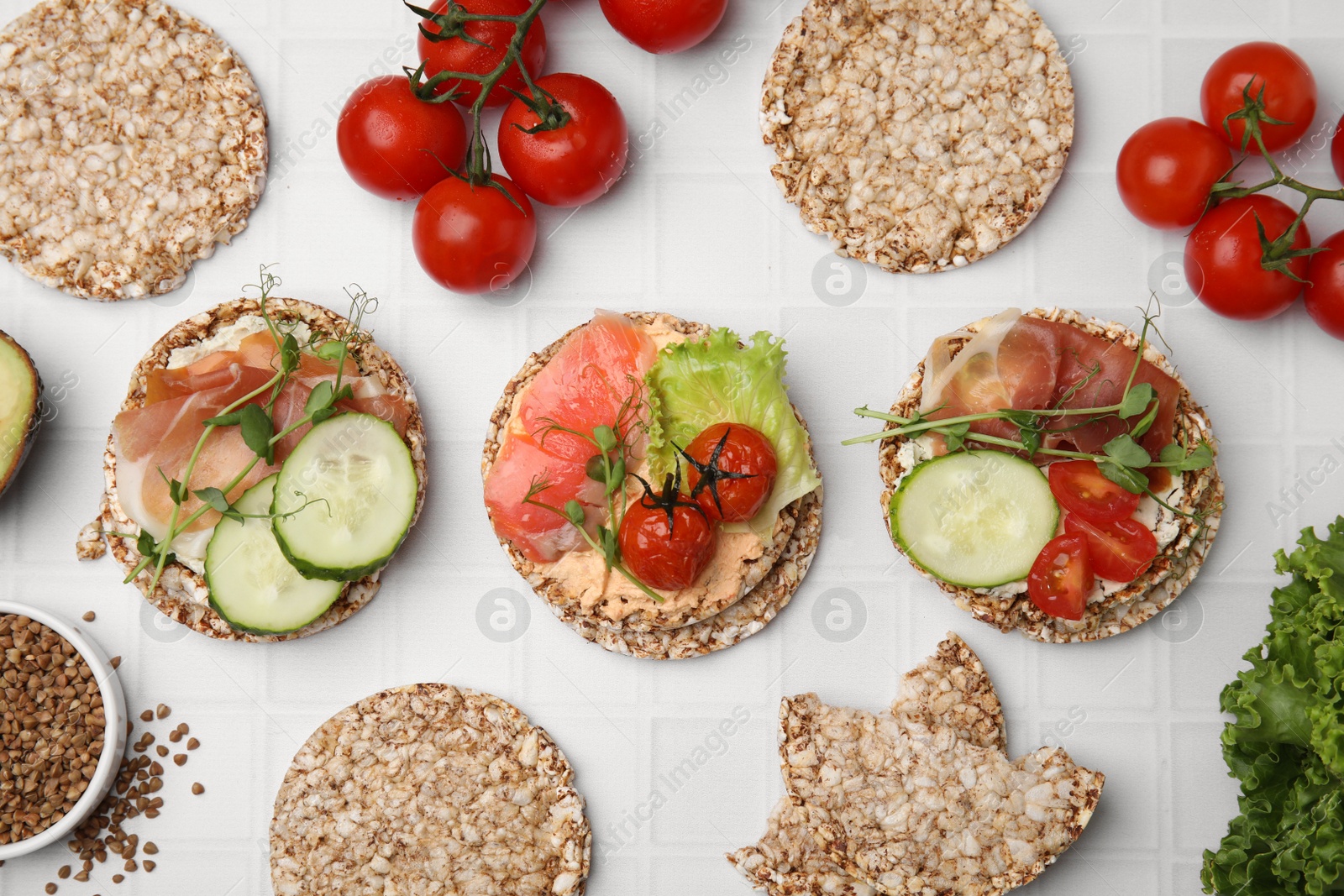 Photo of Set of crunchy buckwheat cakes with different ingredients on white background, flat lay