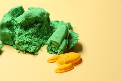 Photo of Bright kinetic sand and plastic toys on beige background, space for text