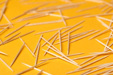 Photo of Disposable wooden toothpicks on orange background, closeup