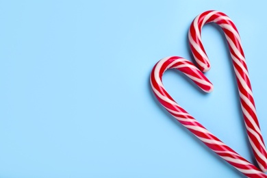 Photo of Heart made of Christmas candy canes on light blue background, flat lay. Space for text