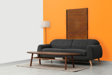 Photo of Stylish room with cosy sofa near orange wall. Interior design