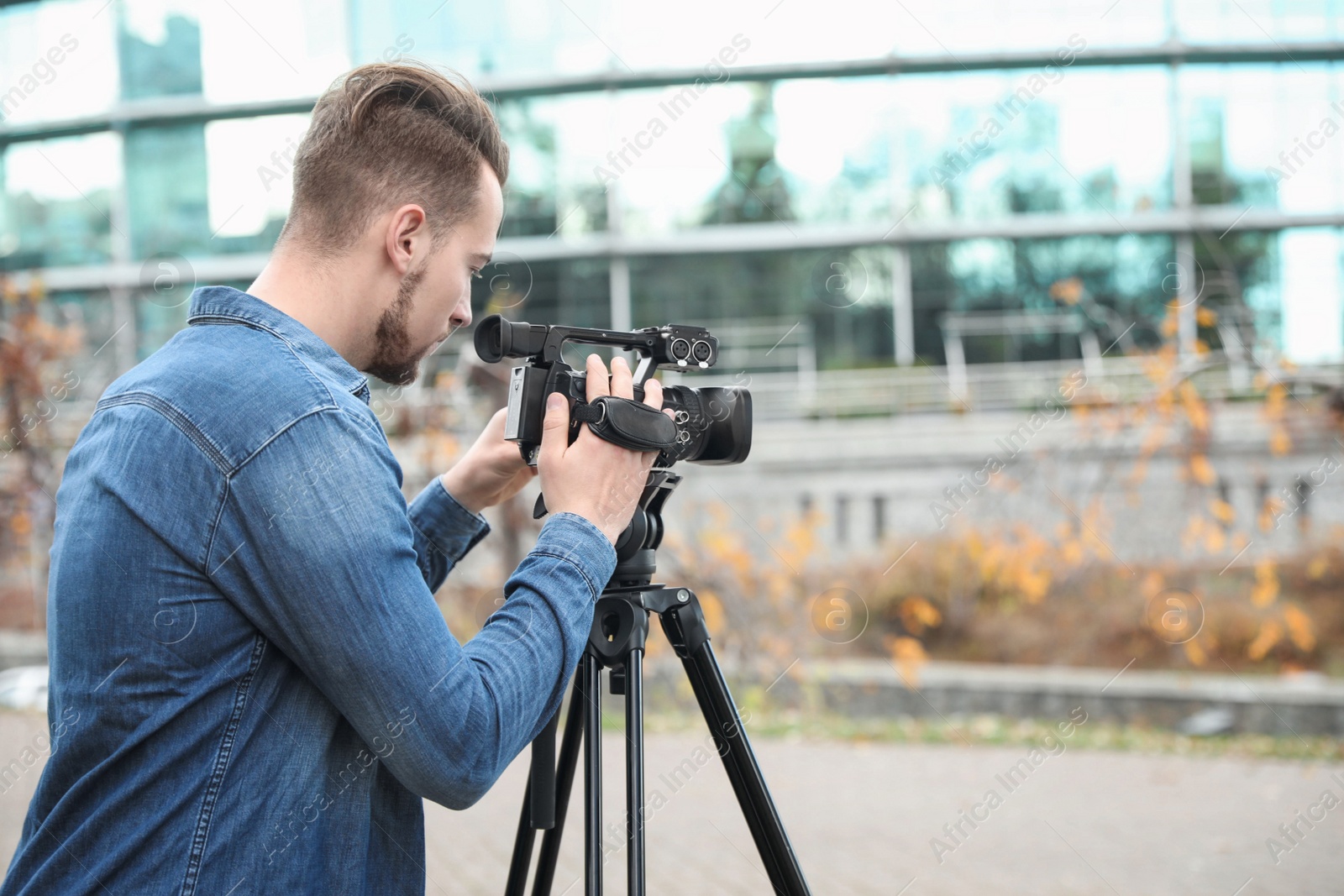 Photo of Video operator with camera working on city street. Space for text