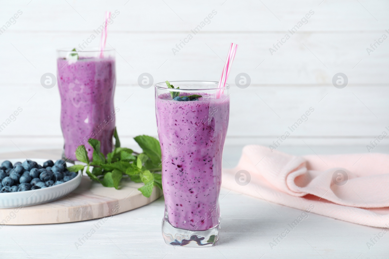 Photo of Glasses of tasty blueberry smoothie on white wooden table