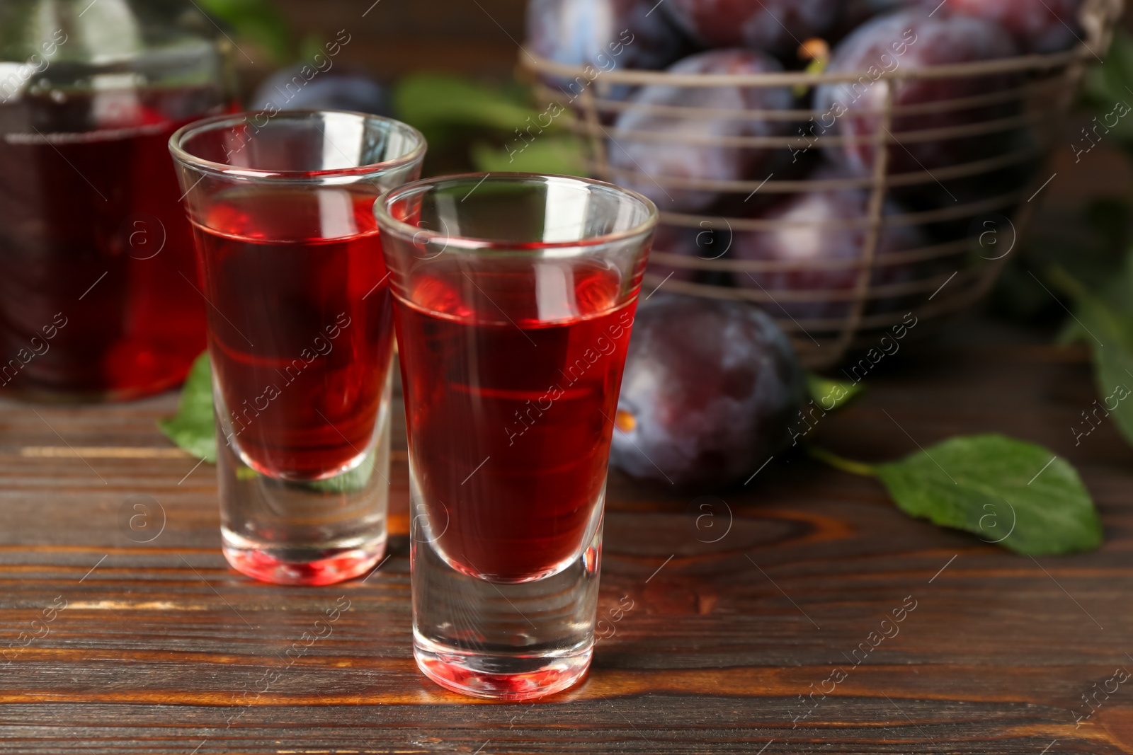 Photo of Delicious plum liquor on wooden table. Homemade strong alcoholic beverage