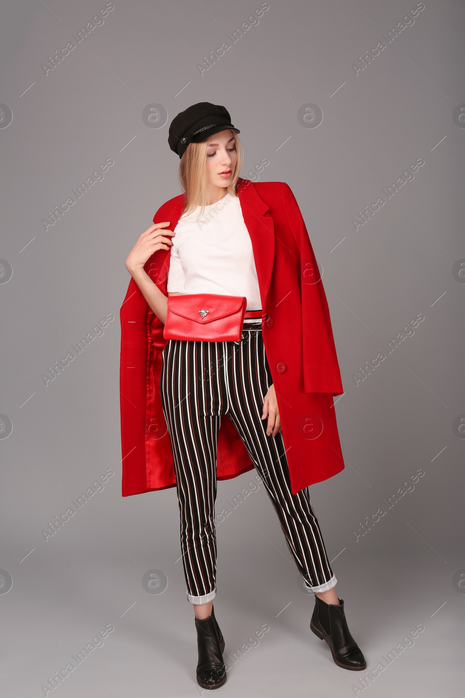 Photo of Young stylish woman in trendy shoes with bum bag on grey background