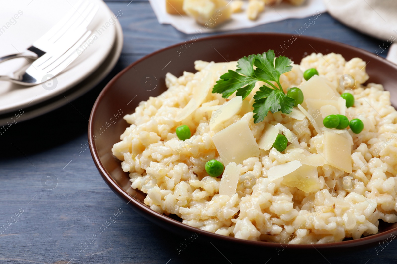 Photo of Delicious risotto with cheese on blue wooden table, closeup