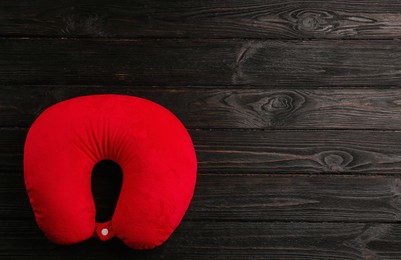 Red travel pillow on wooden background, top view. Space for text