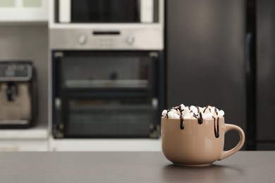 Cup of delicious drink with marshmallows and chocolate on grey table in kitchen. Space for text