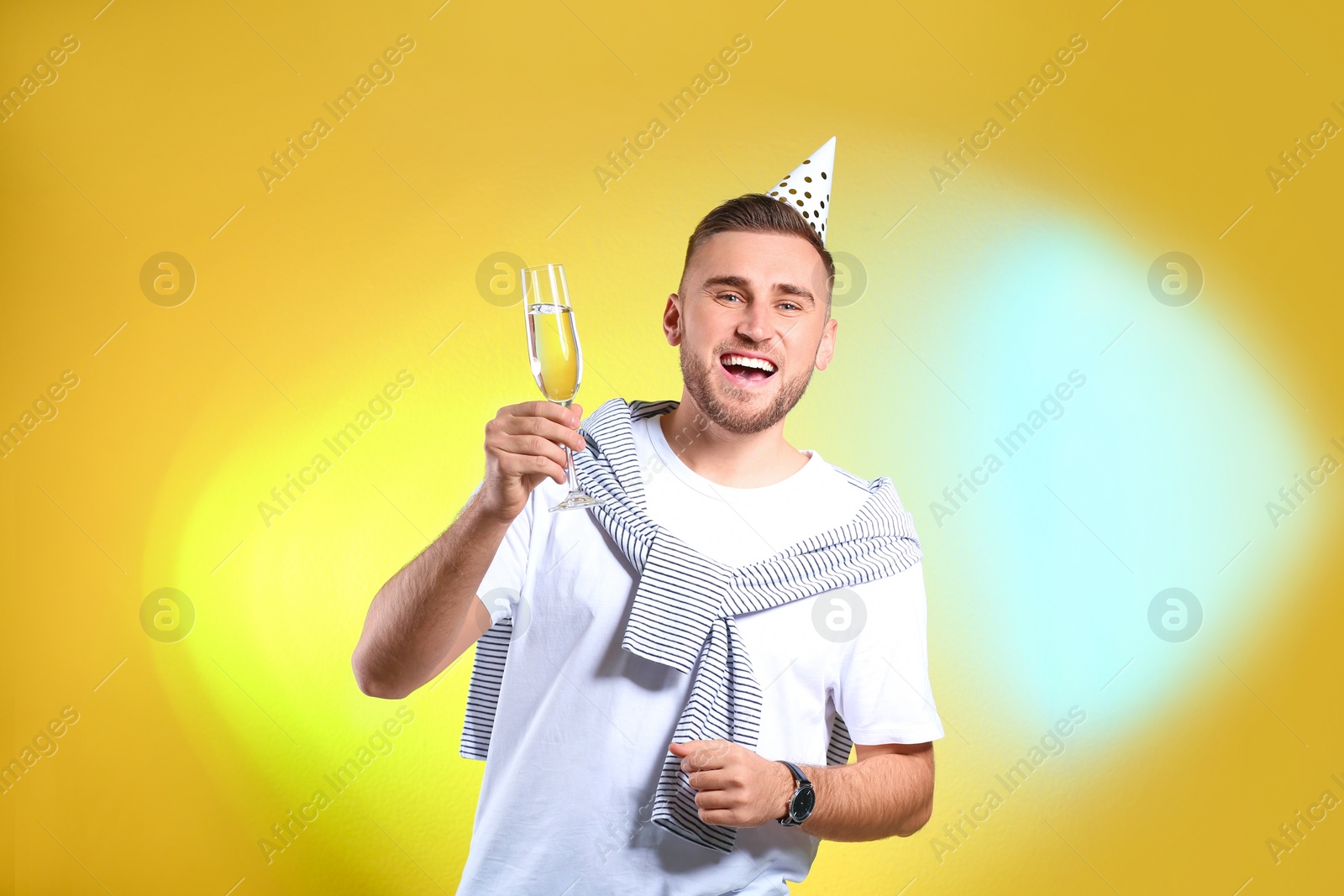 Photo of Portrait of happy man with party cap and champagne in glass on color background