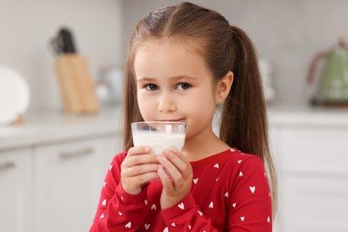 Photo of Cute girl with glass of fresh milk indoors