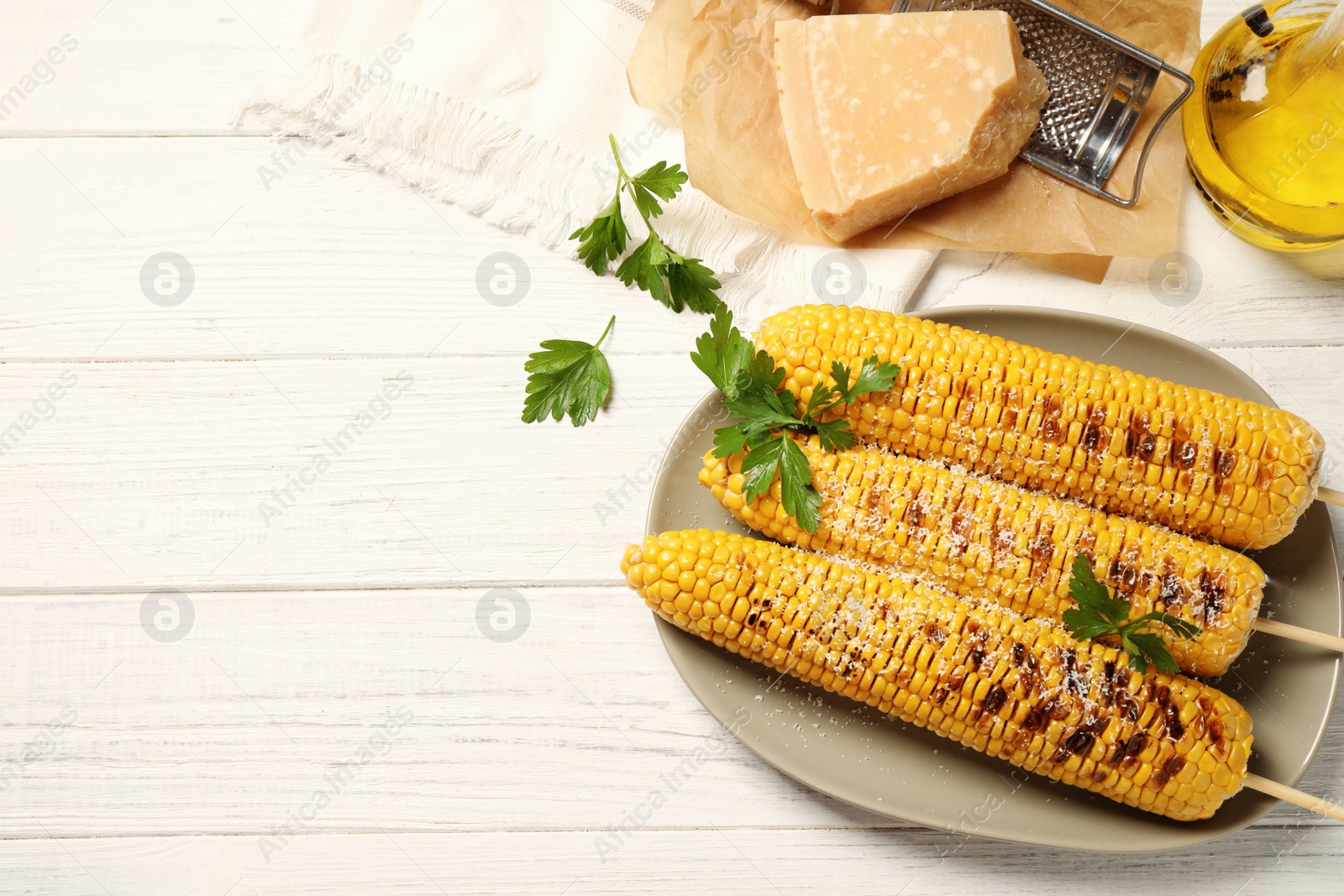 Photo of Tasty grilled corn on white wooden table, flat lay. Space for text