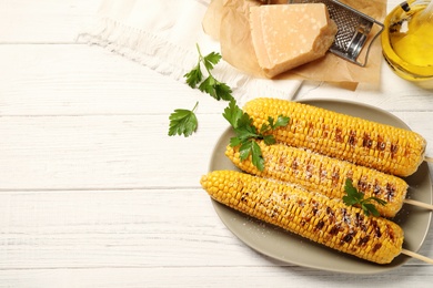 Photo of Tasty grilled corn on white wooden table, flat lay. Space for text