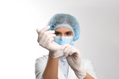 Doctor putting on medical protective glove against white background