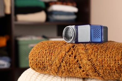 Photo of Fabric shaver on knitted clothes indoors, closeup. Space for text