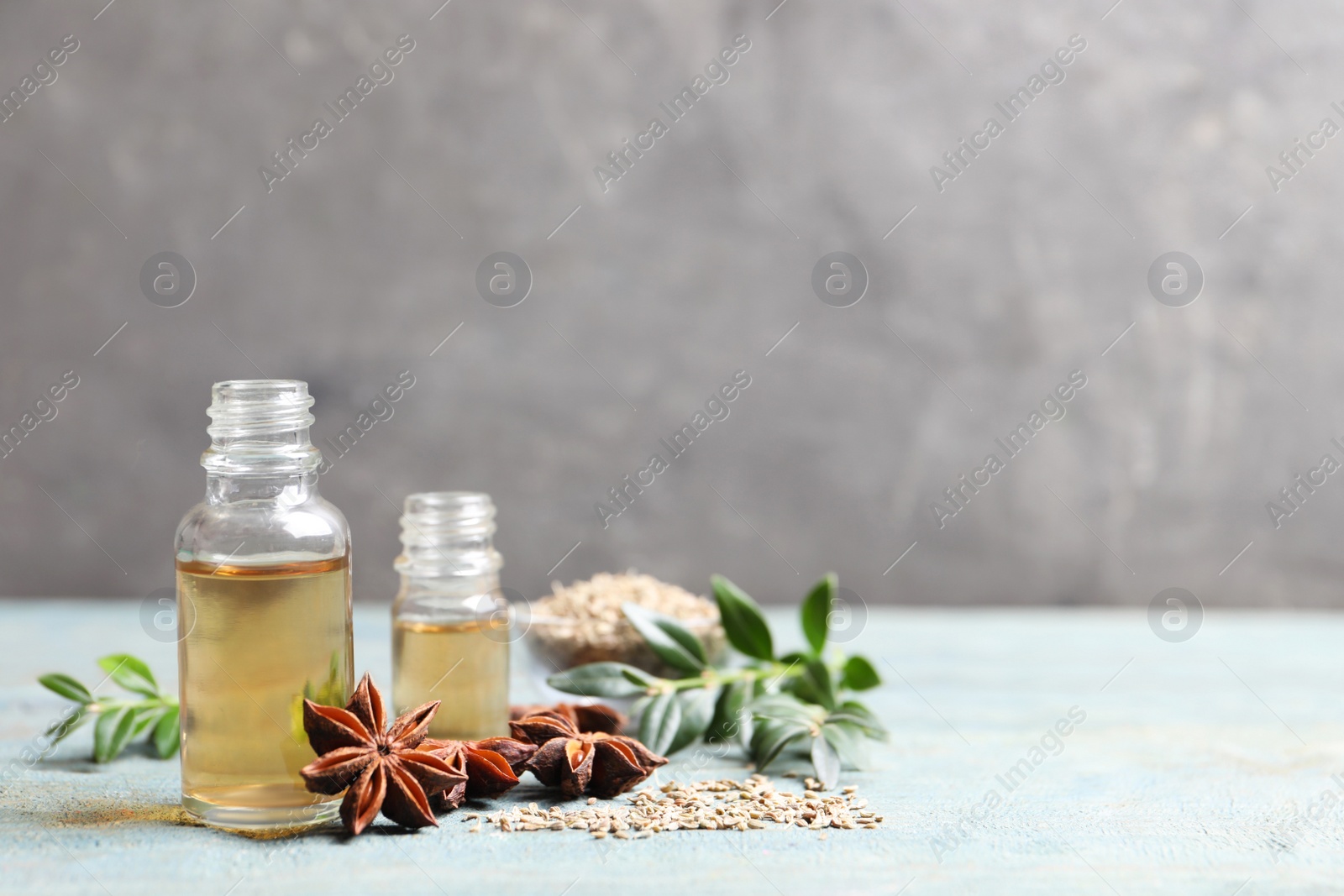 Photo of Anise essential oil and spice on light blue table, space for text