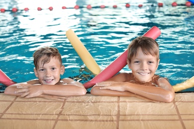 Photo of Little boys with swimming noodles in indoor pool