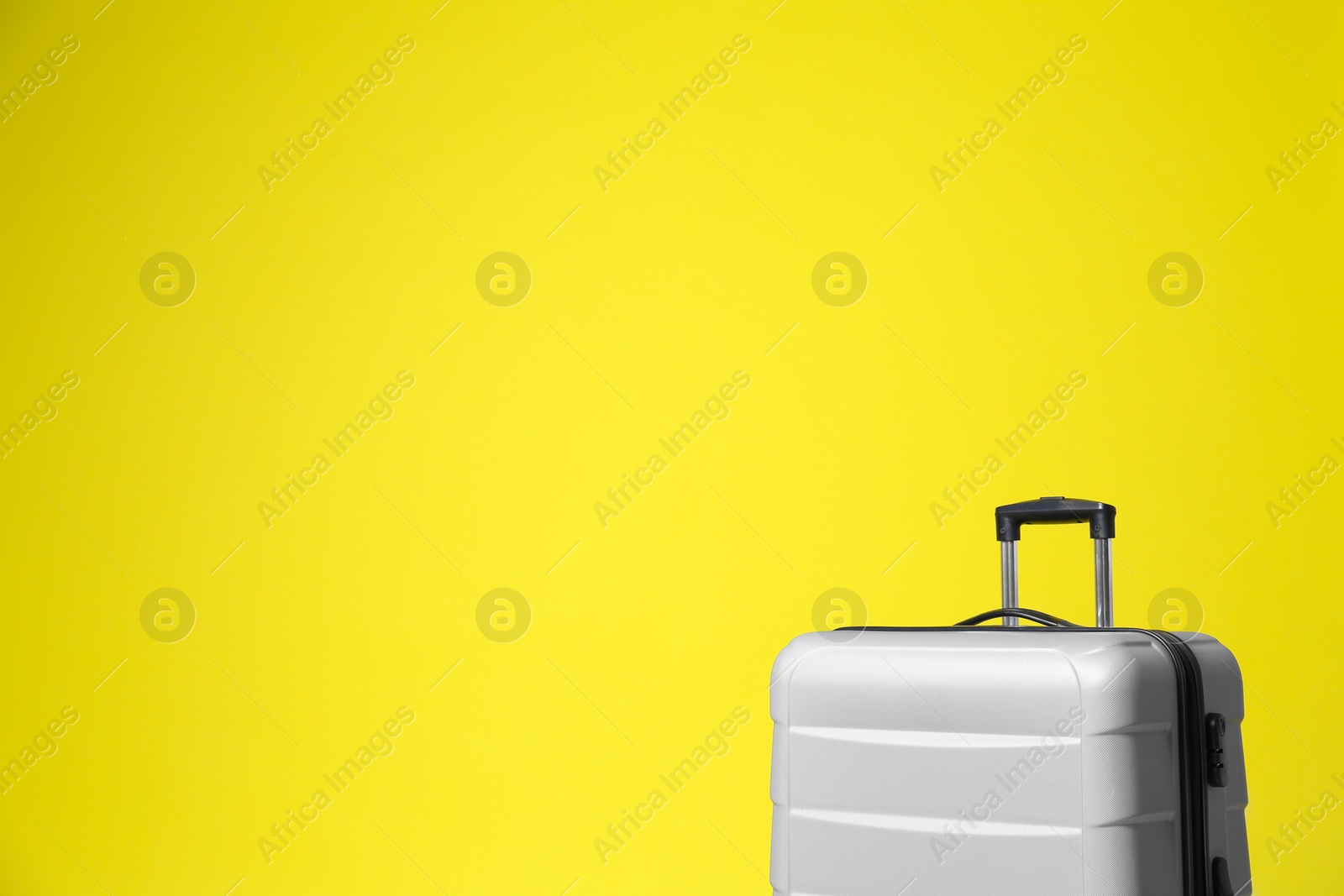 Photo of Stylish grey suitcase on yellow background. Space for text