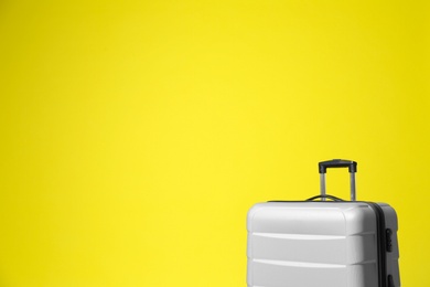 Stylish grey suitcase on yellow background. Space for text